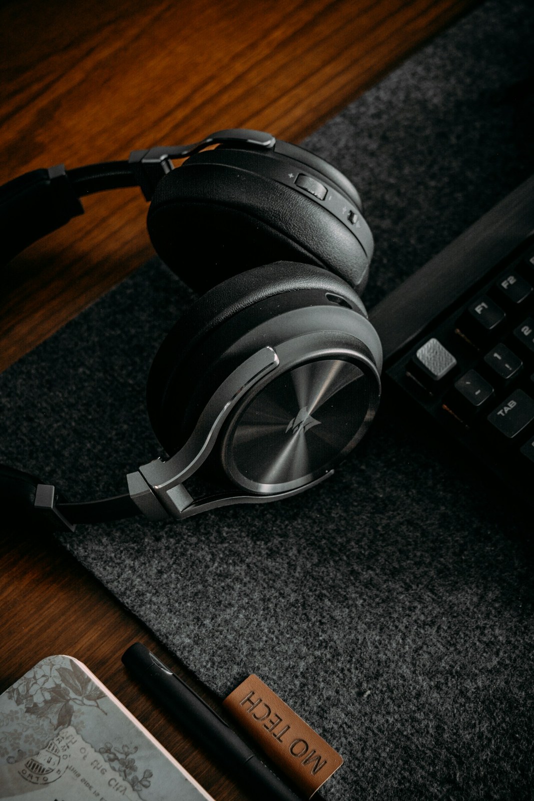 Headphones on a wooden desk beside a keyboard.