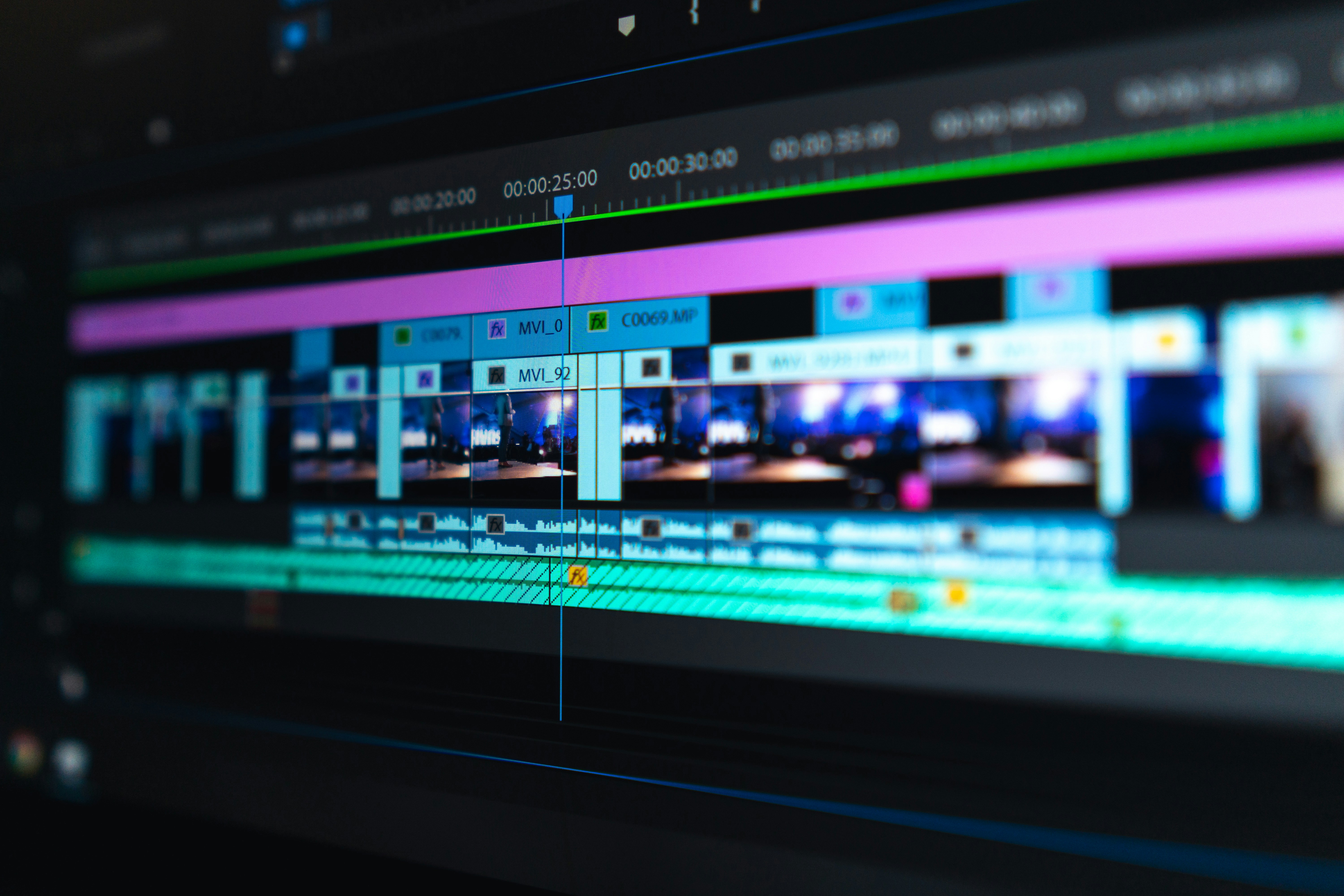 Video editing timeline with waveforms on a dark screen.