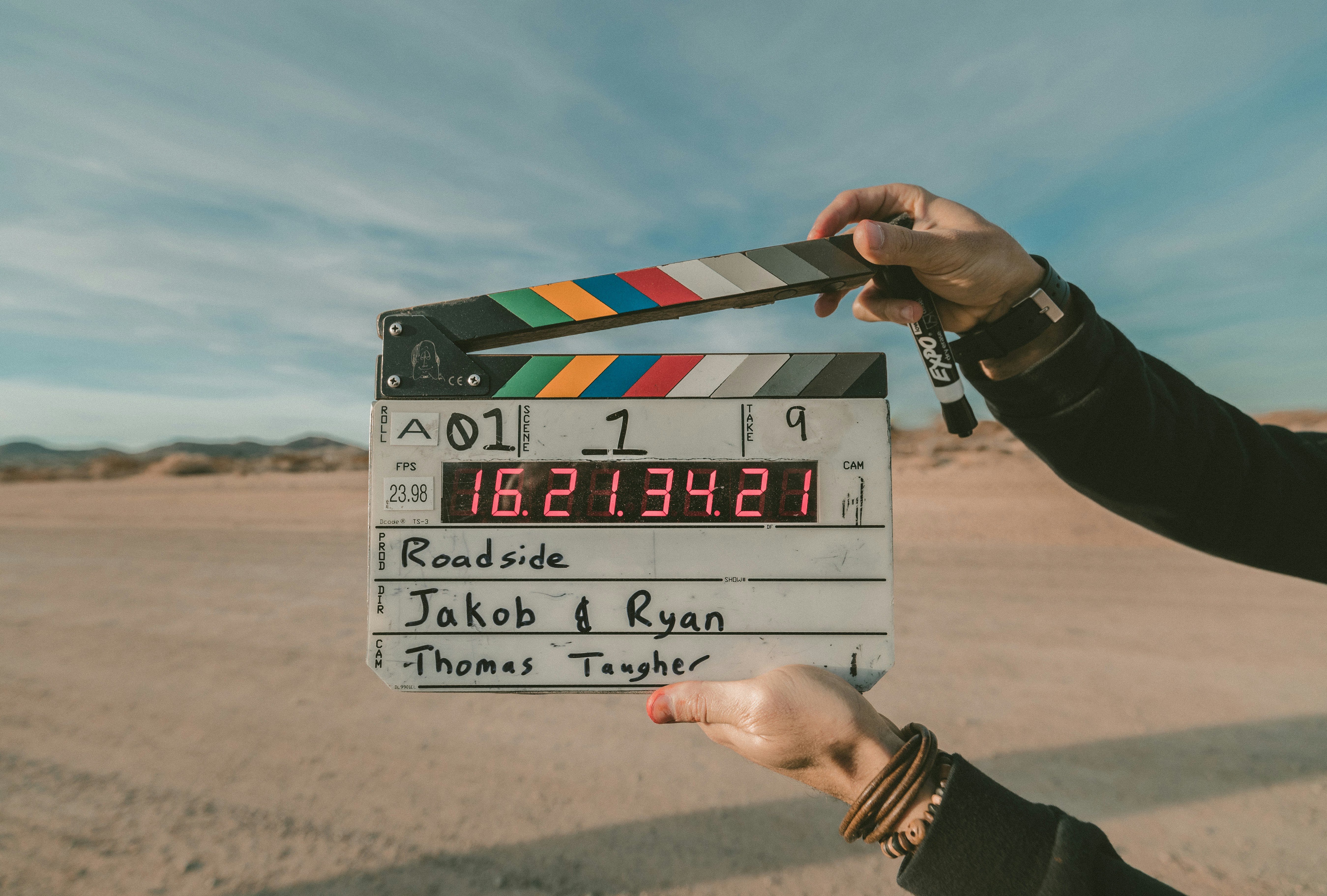 A film clapperboard held up against a desert landscape at sunset.