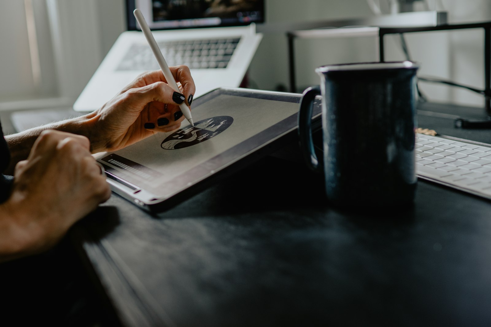 Person drawing on a graphics tablet with a stylus at a desk.