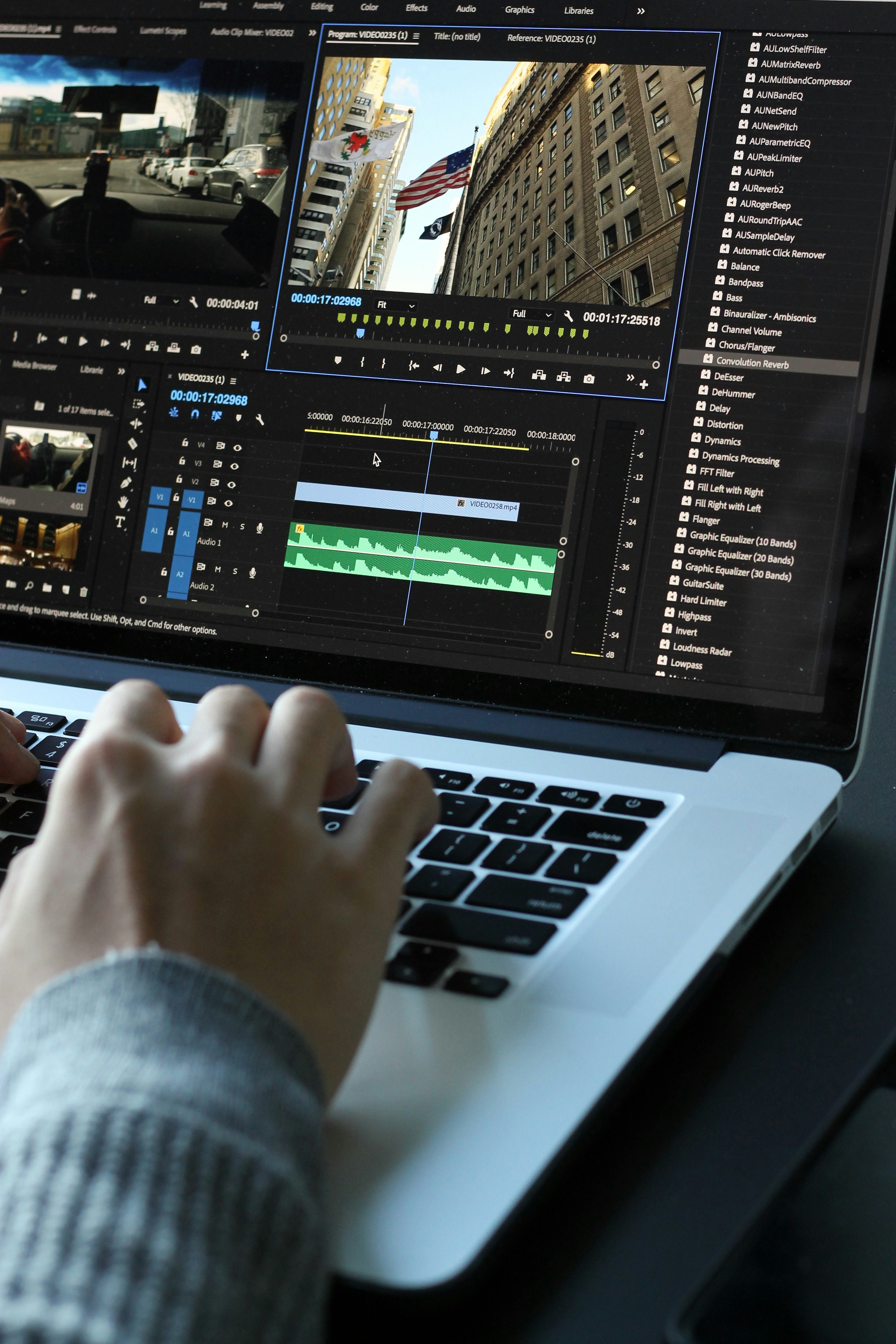 Person using a MacBook Pro with a video timeline open on a second monitor.