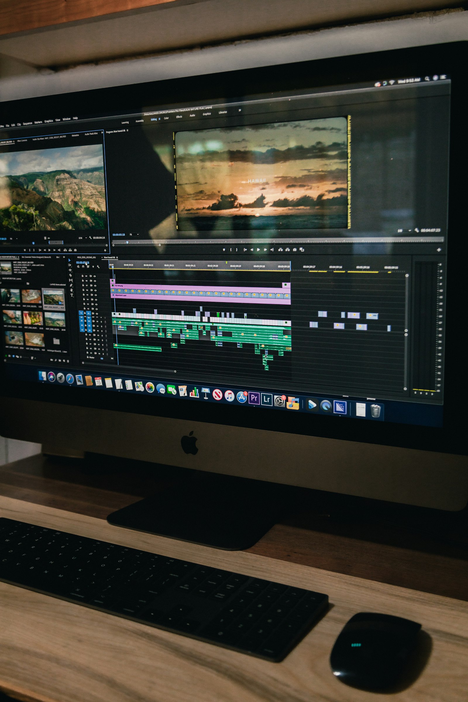 Close-up of hands using a colorful video/photo editing timeline on a widescreen monitor.