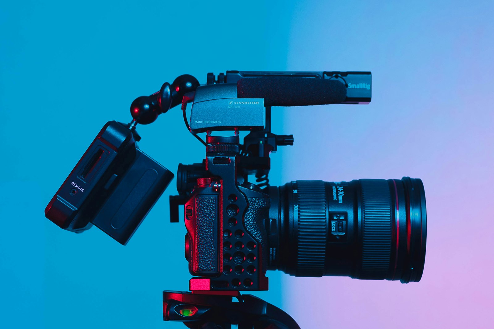 A professional camera with a zoom lens and microphone mounted on a tripod.